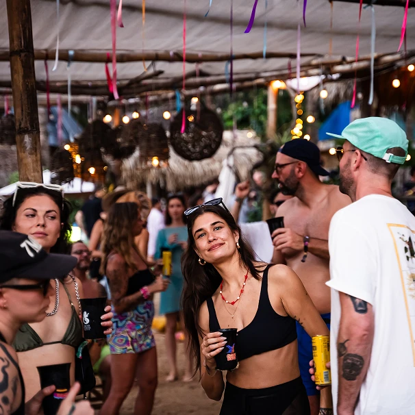A crowd beneath a palm roof