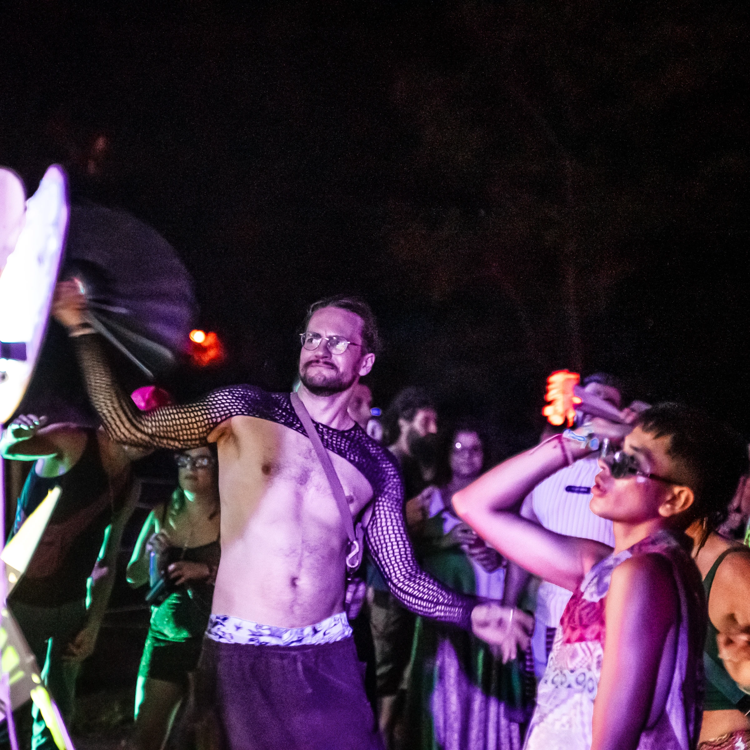 A performer holding a microphone under purple lights